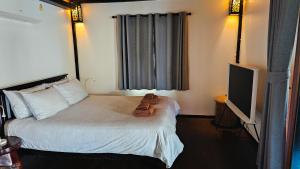 a hotel room with a bed and a television at Baan Moon Fisherman's Villa in Ko Chang