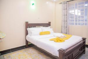 um quarto com uma cama com lençóis brancos e toalhas amarelas em One Bedroom, Lake View with GYM em Nakuru