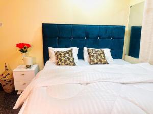 ein großes Bett mit blauem Kopfteil und zwei Kissen in der Unterkunft Downtown Dreamspace City - 3 bedrooms in Daressalam