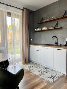 a kitchen with white cabinets and a sink and a table at Donikąd in Wetlina
