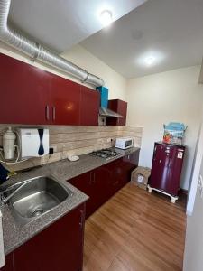 una cocina con armarios rojos y fregadero. en Vibe Villa, en Dehradun