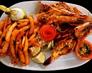 a white plate of food with french fries and seafood at The Beach House by Maasai in Mombasa