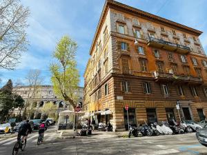 due persone in bicicletta di fronte a un edificio di NEW Colosseum's Custodian Apartment 115 m2 a Roma
