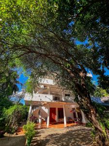 una grande casa bianca con un albero di fronte di Pleasure Island Holiday Home a Dambulla