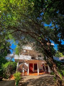 duży biały dom z drzewem przed nim w obiekcie Pleasure Island Holiday Home w mieście Dambulla