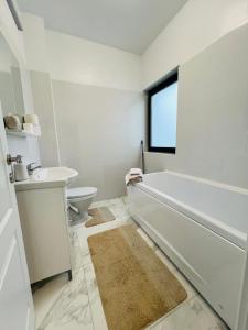 La salle de bains blanche est pourvue d'une baignoire et d'un lavabo. dans l'établissement Apartament zona de case-rezidențiala 2 km de Vivo Mall,curte privata, à Baia Mare