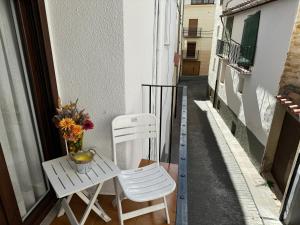 un balcón con 2 sillas y una mesa con flores. en Casa José Morella, en Morella