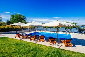 a swimming pool with chairs and umbrellas next to at Duzac in Kraj