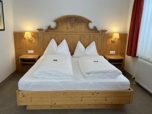 una camera da letto con letto, lenzuola e cuscini bianchi di Landhotel Postgut - Tradition seit 1549 a Tweng