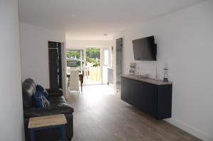 a living room with a couch and a flat screen tv at Swn Y Mor - Sound of the Sea - by Aberporth Beach Holidays in Aberporth