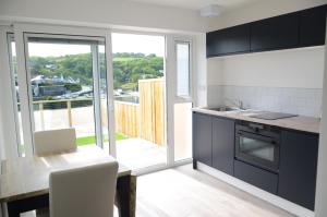 a kitchen with a dining table and a view of a balcony at Swn Y Mor - Sound of the Sea - by Aberporth Beach Holidays in Aberporth
