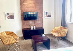 a living room with two chairs and a tv on a wall at Mapungubwe Apartments in Johannesburg