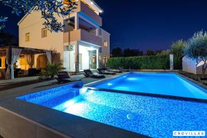 - une piscine en face d'une maison la nuit dans l'établissement Luce, à Zadar