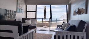 a living room with two couches and a large window at De Valle 37 in Mossel Bay