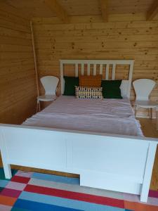 Bett in einem Holzzimmer mit 2 Stühlen in der Unterkunft Wind in den Weiden, Übernachten am Bachlauf in Birstein