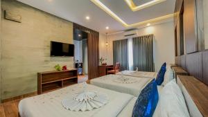 a hotel room with two beds and a television at The Luxury in Siem Reap