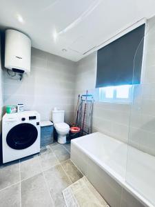 a bathroom with a tub and a washing machine at Brand New St. Julian's Luxury Apartment - Wish Malta in St. Julianʼs