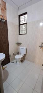 La salle de bains est pourvue de toilettes, d'un lavabo et d'une fenêtre. dans l'établissement Cozy Retreat, à Haridwar