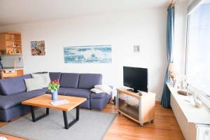 un salon avec un canapé bleu et une télévision dans l'établissement Ferienwohnung-Seetempel-Wohnung-Nr-29, à Scharbeutz