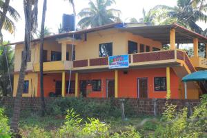 a yellow and orange house with a sign on it at Ruvi Beach front Ac rooms in Gokarna
