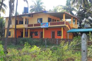 a yellow and orange house with a sign in front of it at Ruvi Beach front Ac rooms in Gokarna