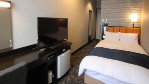 a hotel room with a bed and a flat screen tv at APA Hotel Fukuoka Yukuhashi Ekimae in Yukuhashi