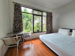 a bedroom with a bed and a table and a window at Villa Montaview Puncak (Mountain View Cottage) in Gadok 1