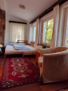 a bedroom with a bed and a couch and windows at Csendes pihenés az erdő mellett - Madárfüttyös Vendégház in Pilisszentlászló