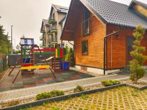 una casa con parque infantil frente a una casa en Resort EDEN - domki, pokoje, apartamenty, en Jastrzębia Góra