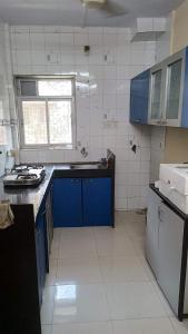 cocina con armarios azules y suelo de baldosa blanca en master bedroom A2, en Bombay