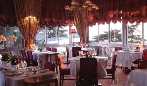 トレブールダンにあるTI AL LANNEC Hotel - Restaurant & Spaの白いテーブルと椅子、窓のあるレストラン