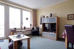 una sala de estar con un televisor y una mesa en Kurpark-Residenz App. 217 Seesicht, en Cuxhaven