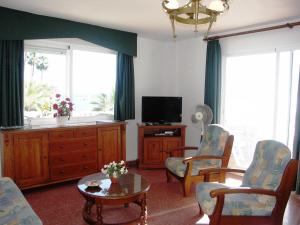 a living room with a tv and chairs and a table at Apartamentos Lual Torrecilla in Nerja