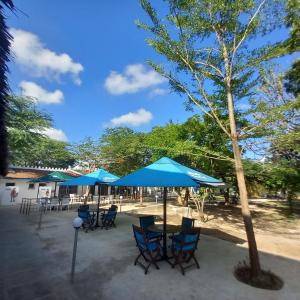 eine Gruppe von Tischen und Stühlen mit blauen Sonnenschirmen in der Unterkunft Maasai Barracks Resort in Mombasa