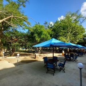 Maasai Barracks Resort في مومباسا: طاولة وكراسي تحت مظلة زرقاء