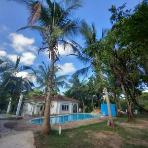 a house with a swimming pool between two palm trees at Maasai Barracks Resort in Mombasa