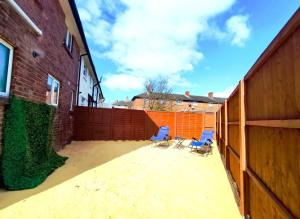 two blue chairs sitting on a patio next to a fence at Comfortable 3 Bedrooms Leeds Beach House - Ideal for Family and Contractors - Free WIFI, Projector in bedroom and Free Parking for 2 cars in Killingbeck