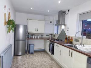 a kitchen with white cabinets and a stainless steel refrigerator at Leeds Beach House, Free Parkings, Sandy private backyard, 70 Inch Smart Tv, X box, Large gardens Included in Killingbeck
