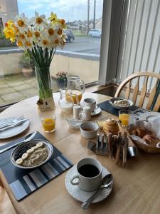 a table with breakfast foods and a vase of flowers at Marine Villa B&B in Annalong