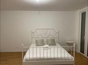 - un lit blanc avec 2 oreillers dans l'établissement Logement spacieux proche de Lausanne, à Crissier