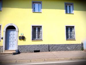 un edificio amarillo con una puerta y ventanas azules en Chrizia en Novi Ligure