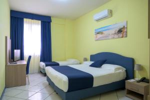 a hotel room with two beds and a television at Hotel Centro Congressi Polo Nautico in Salerno