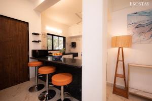 a kitchen with a counter and stools in a room at EKOSTAY - Casa Paradiso in Alibaug