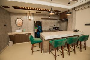 a kitchen with a counter and green chairs at Shaira Garden Hotel & Resorts in Nārāyanganj