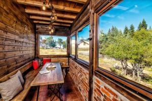 een houten kamer met een tafel, stoelen en ramen bij Вила Приказка in Zar-Kalojan