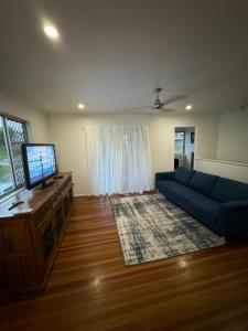 ein Wohnzimmer mit einem blauen Sofa und einem TV in der Unterkunft Spacious Home with Large Entertainment Area in Rockhampton