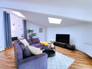 ein Wohnzimmer mit einem lila Sofa und einem TV in der Unterkunft Großes modernes Loft mit Tischkicker und Billiard in Uni und Klinik Nähe in Magdeburg