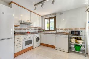 een keuken met witte kasten en een wasmachine en droger bij Mirador 31 Roses - Immo Barneda in Roses