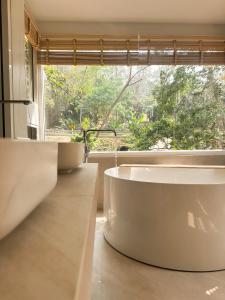 La salle de bains est pourvue d'une grande baignoire et d'une fenêtre. dans l'établissement Arb Pa Home and Cafe @ Mae on, à Chiang Mai