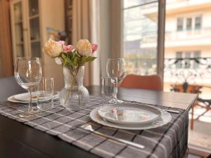 una mesa con un jarrón de flores, platos y vasos en Carla's Residences F1 Hyper Centre, en Aix-les-Bains